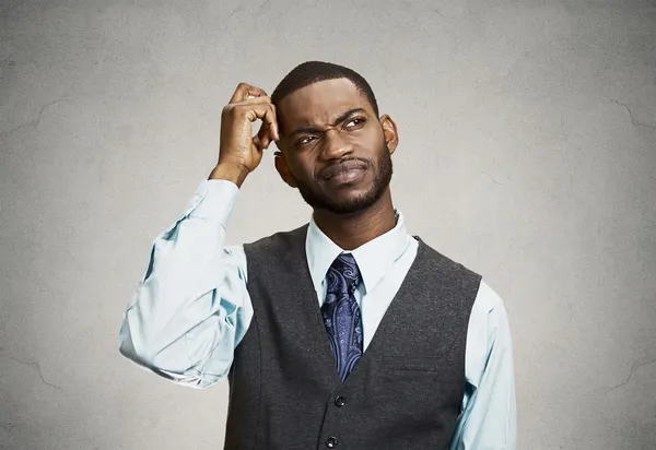 A confused man scratching his head in thought