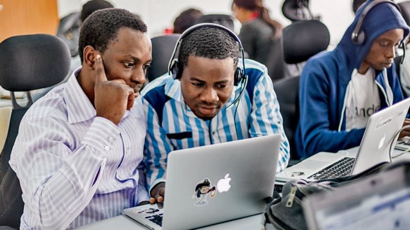 2 African guys working on a macbook computer.