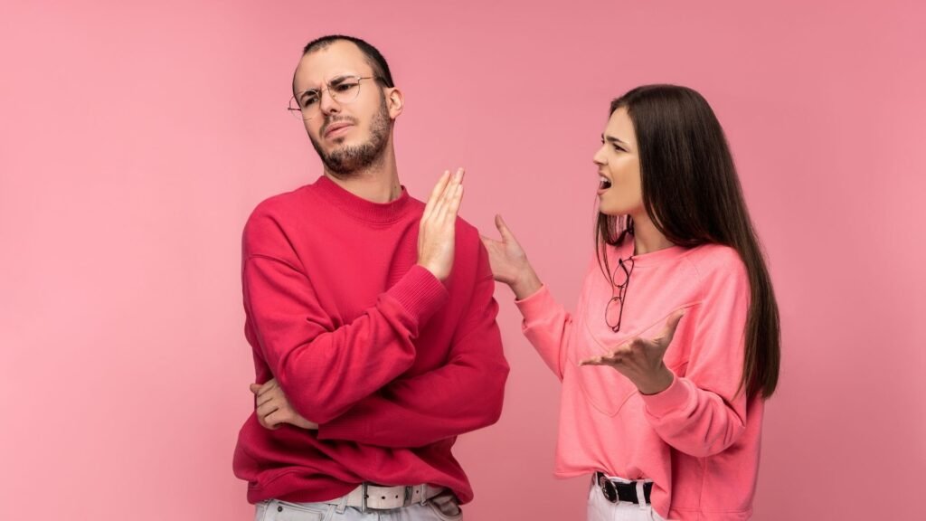 An outraged woman and annoyed man in pink and red sweeaers respectfully