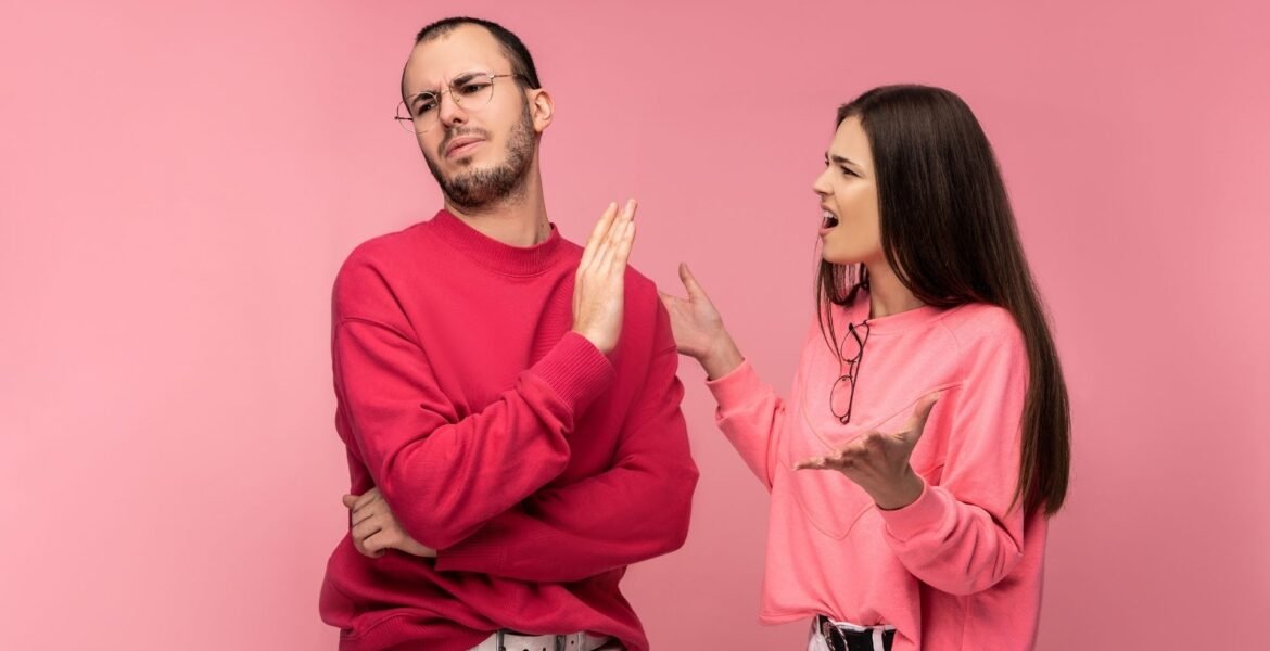 An outraged woman and annoyed man in pink and red sweeaers respectfully