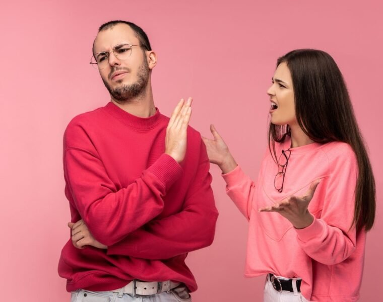 An outraged woman and annoyed man in pink and red sweeaers respectfully